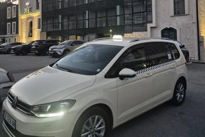 Taxi outside a glass-fronted hotel in Albena at dusk