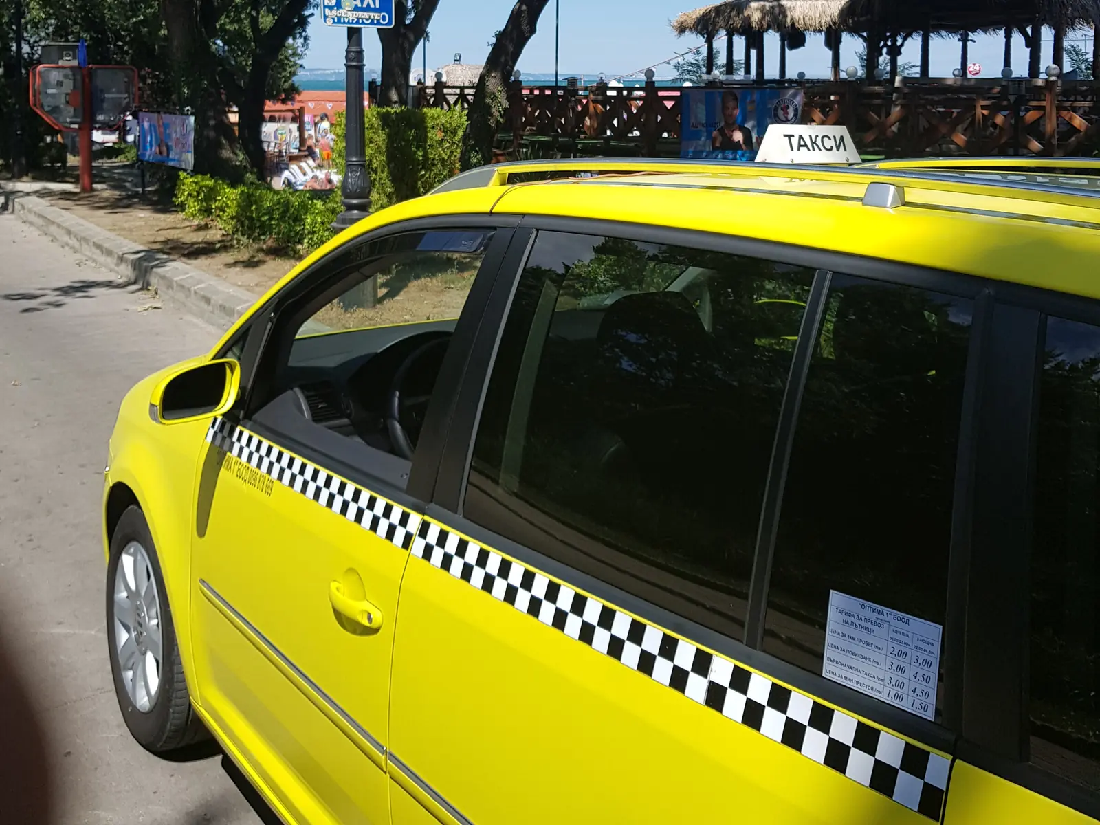 Yellow taxi on a tree-lined street beside the sea in Albena